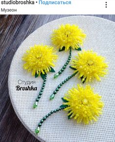 three yellow flowers sitting on top of a white plate with beaded thread and beads