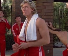 two men in matching red and white outfits, one is holding a towel over his head