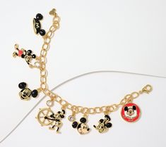 the mickey mouse charm bracelet has many charms on it's link and is attached to a gold chain