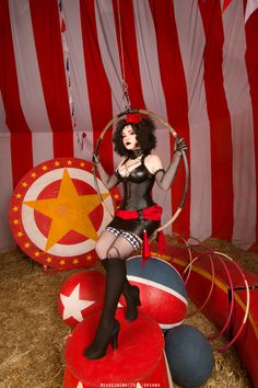 a woman dressed in black and red is sitting on top of a circus float with hoop