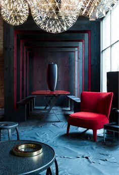 a red chair and table in a room with chandeliers hanging from the ceiling