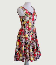 This mesmerizing 1950s style swing dress is adorned with an allover print of blooming garden florals that will make you feel like you're walking through a blossoming paradise. With its sleeveless design and flattering V-neckline both in the front and back, it exudes elegance and grace. Perfect for those sunny summer days, this dress also features convenient side pockets to keep your essentials close at hand. This beauty effortlessly embraces your figure with a simple back zipper closure.Availabl 1950s Style Sleeveless Floral Print Vintage Dress, 1950s Style A-line Vintage Dress With Floral Print, 1950s Sleeveless Floral Print Dress, Multicolor Floral Print Sleeveless V-neck Dress, 1950s Floral Print A-line Dresses, Blooming Garden, Black Garden, 1950s Style, 1950s Fashion