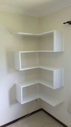 an empty room with white shelving in the corner and tile flooring on the ground