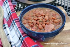 a blue bowl filled with meat and beans on top of a wooden cutting board next to an instant pressure cooker