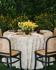 the table is set for two with yellow flowers in vases