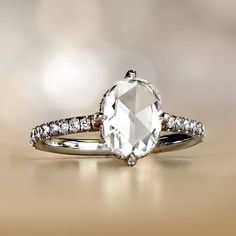 an engagement ring with a white topazte and diamond accents on the band, set in 18k gold