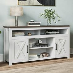 a white entertainment center with two doors and shelves on each side, in a living room