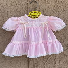 "Cute pink dress in a size medium look to be 3/6 months but please check measurements. Lace part has a little discoloration on middle bib part see photo.. Arms are loose and it has a little black spot on back. See all photos. Two button back Shoulder to hem 11\" Pit to pit 10\"" Pink Cotton Dress With Ruffles, Pink Long Sleeve Vintage Dress For Summer, Pink Short Sleeve Cotton Dress, Short Sleeve Ruffled Vintage Dress For Dress-up, Short Sleeve Vintage Dress With Ruffles For Dress-up, Pink Sleeveless Vintage Dress With Ruffles, Vintage Summer Dresses For Playtime, Vintage Dresses For Summer Playtime, Summer Vintage Dresses For Playtime