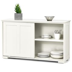 a white cabinet with plates and bowls on it's shelf next to a potted plant