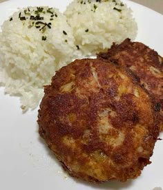 two crab cakes on a white plate with rice