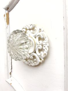 a white door handle with an ornate design on it's side and a glass knob in the middle