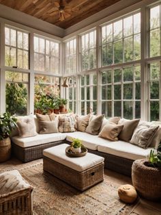 a living room filled with lots of windows and furniture next to a large window covered in plants