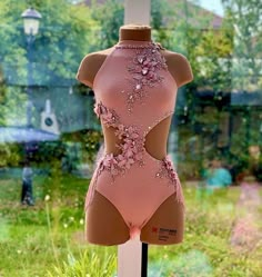 a mannequin in a pink bodysuit with flowers on it's back