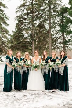 bride and her bridesmaids in the snow with their bouquets wrapped around them