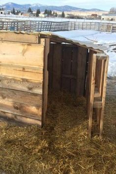 a wooden outhouse sitting on top of dry grass