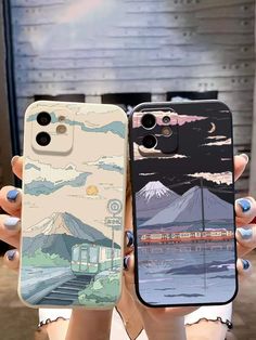 two people holding up their cell phones in front of the same phone case with mountains and clouds on them