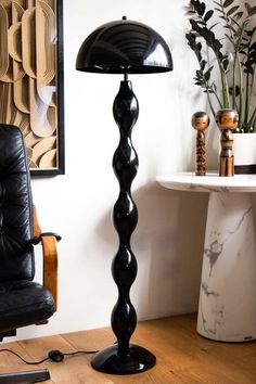 a black lamp sitting on top of a wooden floor next to a chair and table