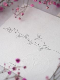 some pink flowers and white paper on a table