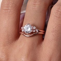 a woman's hand with a diamond ring on top of her finger and an engagement band