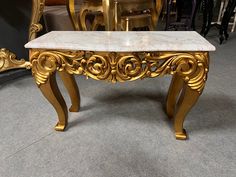 a marble top table with gold accents in a showroom area, surrounded by chairs and tables