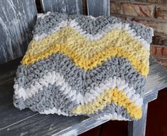 a gray and yellow blanket sitting on top of a wooden bench