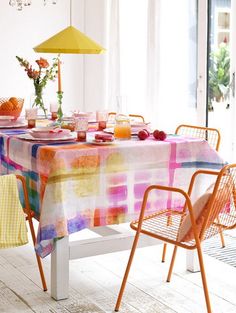 the table is covered with colorful cloths and place settings for two people to sit at