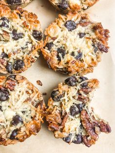 several cookies with raisins and blueberries are arranged on a piece of parchment paper