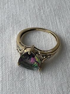 Lots of flash and colour in this lovely 14K yellow gold and trilliant cut mystic topaz ring.   Single diamonds on either side of the topaz offer a bit more subtle sparkle.  The only mark on the band is an R in a circle.  Both diamonds and topaz tested on my gem tester, the gold has been jeweller tested as 14K.  On my mandrel the ring fits to size approx. 6.5 (halfway between 6 1/2 - 6 3/4)  I try to provide as much information as possible about the size of a ring but if more measurements are nee Luxury Topaz Rings With Stone Setting, Luxury Silver Polished Topaz Ring, Luxury Topaz Gemstones For Weddings, Luxury Trillion Cut Topaz Ring For Formal Events, Luxury Teardrop Topaz Ring In Fine Jewelry Style, Luxury Trillion Cut Topaz Ring For Formal Occasions, Luxury Gift Topaz Ring With Diamond Accents, Luxury Elegant Trillion Cut Topaz Ring, Luxury Unique Topaz Ring For Women