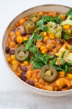 a bowl filled with beans and vegetables on top of a white countertop next to a spoon