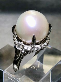 A classically designed cocktail ring done in platinum and centered by a genuinely beautiful South Sea pearl with a beautiful even luster and color measuring 14.50mm. Surrounding the central pearl is .46cttw in round and baguette diamonds ranging G-I in color and Vs1-Si1 in clarity. Diamond weight is stamped inside the shank. Dimensions/Weight: Ring measures .70" in diameter and weighs 12.6g. Size 8 (sizable). Condition: All stones are secure and in perfectly wearable condition. R-GJSYE Elegant White Gold Diamond Ring With Cabochon, Classic White Pearl Ring With Diamond Accents, Classic Brilliant Cut Diamond White Pearl Ring, Classic White Gold Pearl Ring With Diamond Accents, Timeless White Gold Pearl Ring With Center Stone, Formal Brilliant Cut Pearl Ring, Formal White Pearl Ring With Center Stone, Classic Pearl White Diamond Ring For Formal Occasions, Classic White Gold Akoya Pearl Ring