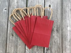 six red paper bags are sitting on a wooden table, with twine around them