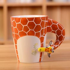 a giraffe print coffee mug with a toy giraffe on it