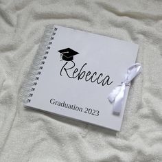 a book with a graduation cap on it sitting on top of a white bed sheet