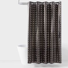 a black and white shower curtain with polka dot print on the bottom, in front of a bathtub