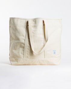 This Large East West Tote from Immodest Cotton is the perfect bag for weekend getaways and trips to the farmers market. With double stitched seams and removable leather handles, this cotton canvas shoulder bag converts to a handheld tote with ease. Not to mention - we love this neutral shade of canvas. Details + Design: Converts from handheld to shoulder with detachable leather handles. Remove the leather handles to wash. One interior pocket. Material: Cotton canvas. Undyed leather handles. Hand Classic Cotton Canvas Bag, Classic Cotton Shoulder Bag For Everyday, Everyday Canvas Bag With Duck Canvas Lining, Beige Canvas Travel Bag With Double Handle, Classic Cotton Canvas Bag For Everyday Use, Travel Shoulder Bag With Reinforced Handles In Waxed Canvas, Eco-friendly Waxed Canvas Bag With Canvas Lining, Cotton Shoulder Bag For Travel, Casual Canvas-lined Shoulder Bag For Weekend