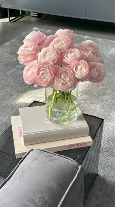 a glass vase filled with pink roses sitting on top of a table next to two books