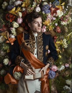 a man dressed in an elaborately decorated suit and holding a box surrounded by flowers