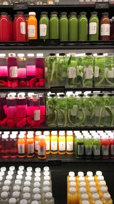 many different colored juices are on display in a store shelf, with one being green and the other is red