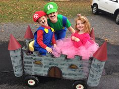 two children dressed up as mario and luigi are riding in a toy car with an adult