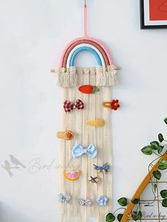 a wall hanging with buttons and bows on it next to a plant in a room