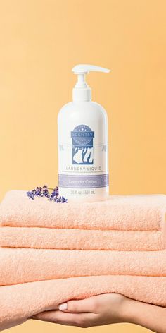 a person holding towels and soap in front of an orange background with the words lavender liquid on it