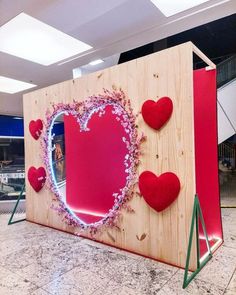 a large wooden box with hearts on the side and a mirror in the middle that has flowers growing out of it