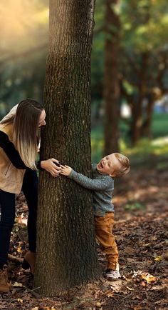 a woman and child are standing next to a tree