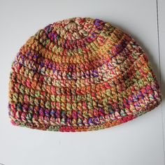 a multicolored knitted hat sitting on top of a white table