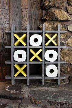 a wooden rack with toilet paper and two rolls on it next to a stone wall