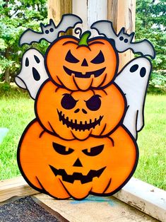 three carved pumpkins sitting on top of each other in front of a wooden fence