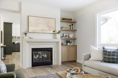 a living room filled with furniture and a fire place in front of a window on top of a hard wood floor