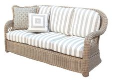 a wicker couch with blue and white striped pillows on it's armrests