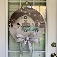 a christmas door hanger with a truck and snowman on it, hanging from the front door