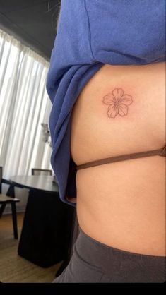 a woman's stomach with a small flower tattoo on her lower back and side